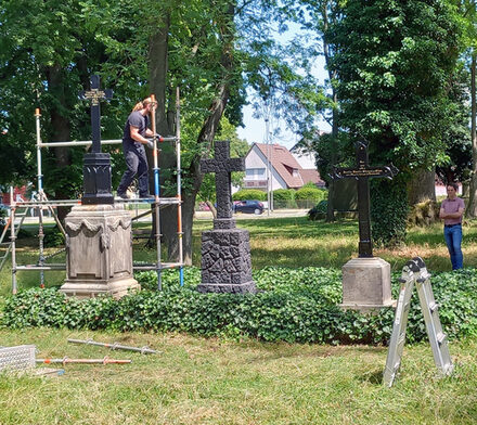 Adrian Sievers sieh Andreas Müller beim Aufbau der Grabkreuze zu.
